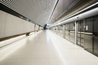 An empty metro platform with full-height screen doors, the driverless station format behind the Riyadh Metro map
